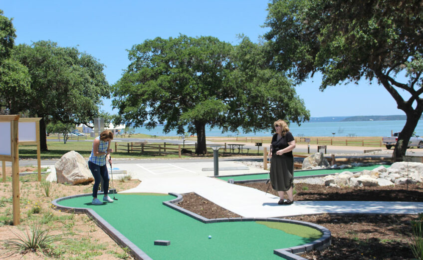 Margo Richards (left), vice president of Community Resources for the Lower Colorado River Authority, and Clara Tuma, public information officer for the LCRA, laugh at Richards’s first shot on hole No. 1 at the new Lake Buchanan Mini Golf course at Black Rock Park. Staff photo by Jennifer Fierro