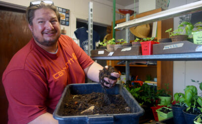 Brian Fraus, owner of Texas Big Worm Farm in Bertram, holds a bin of compost, complete with coffee grounds and filters, that he uses to nourish seedlings for his garden, some of which brighten up his office on a cloudy March afternoon. Staff photo by Suzanne Freeman