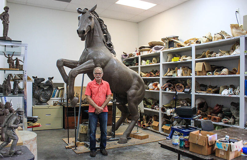 Smithwick artist Dan Pogue stands with his larger-than-life sculpture ‘Warriors,' which towers over him at 15 feet. Staff photo by JoAnna Kopp