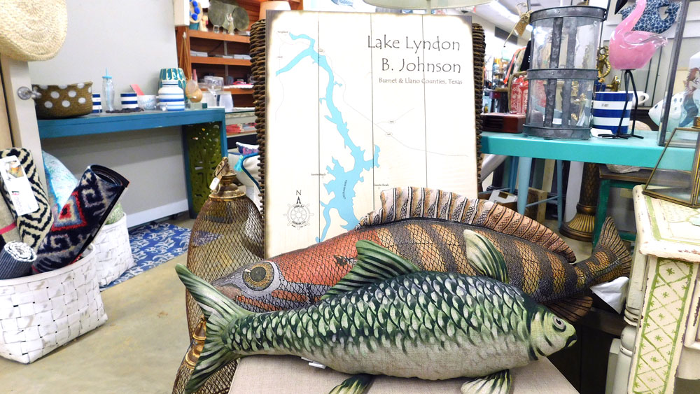 Included in the many Highland Lakes-inspired souvenirs at Ford & Crew Home Hardware are wooden wall maps of Lake LBJ and fish pillows. Staff photo by Jennifer Greenwell