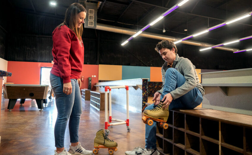 Kasey Faurie, the marketing coordinator at Putters and Gutters in Marble Falls, instructs 101HighlandLakes.com staff writer Nathan Bush on how to lace up his skates to help him maintain his balance and stability. Staff photo by Dakota Morrissiey