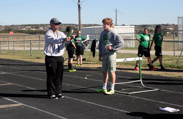 Burnet Middle School boys coordinator Jerod Rye (left) demonstrates the proper way to hold a baton to Kade Strong. Rye was voted the favorite Burnet-area coach in the 2015 Locals Love Us awards. Staff photo by Jennifer Fierro