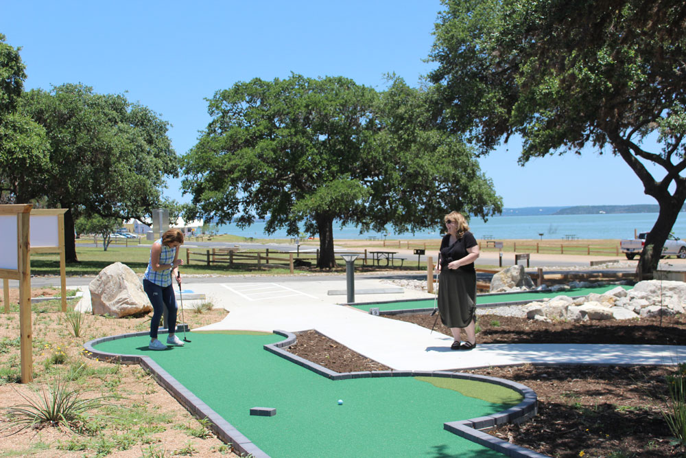 Margo Richards (left), vice president of Community Resources for the Lower Colorado River Authority, and Clara Tuma, public information officer for the LCRA, laugh at Richards’s first shot on hole No. 1 at the new Lake Buchanan Mini Golf course at Black Rock Park. Staff photo by Jennifer Fierro